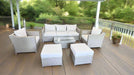 Outdoor patio furniture set on a wooden deck with a green garden background