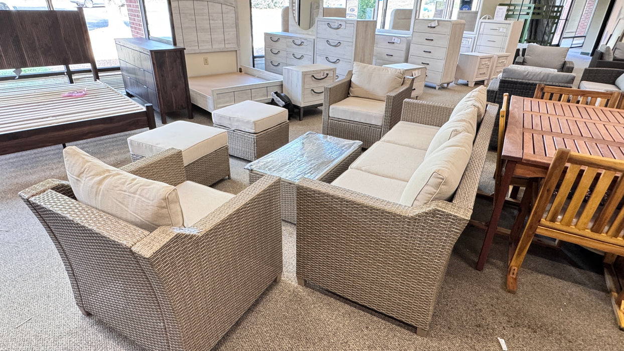 Outdoor furniture set with beige cushions on a showroom floor.